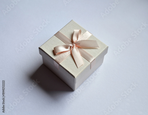White gift box with gold ribbon and bow on black background for Christmas holiday celebration present surprise