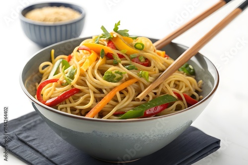 Stylish bowl of hakka noodles with vibrant vegetables and chopsticks arranged in a clean modern advertising composition - AI Generated