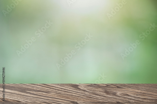 Wooden table surface with blurred green natural background for product placement