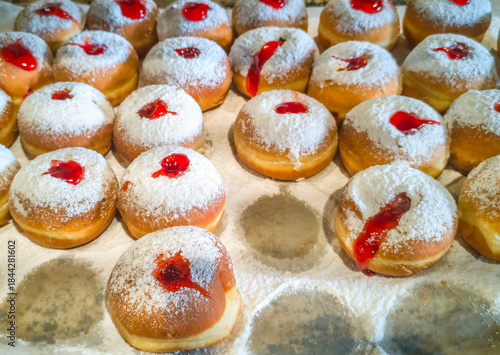 Morning sale of sweet donuts (sufganiot) for Hanukkah Jewish Holiday, close-up shot done in a local market place in bakery. Focus on foreground 