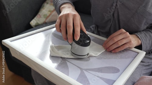 woman takes care of clothes at home, cuts off lint with tool