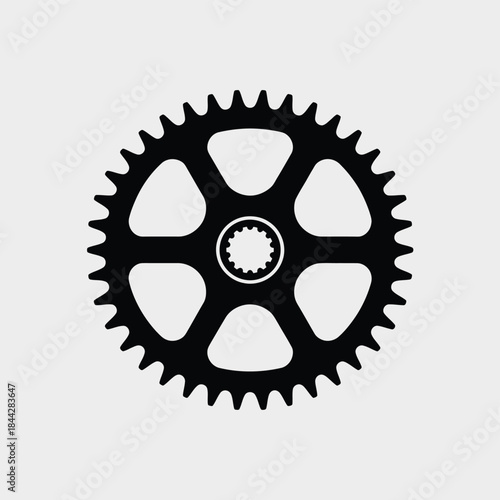 A simple black silhouette of a bicycle chainring gear on a gray background