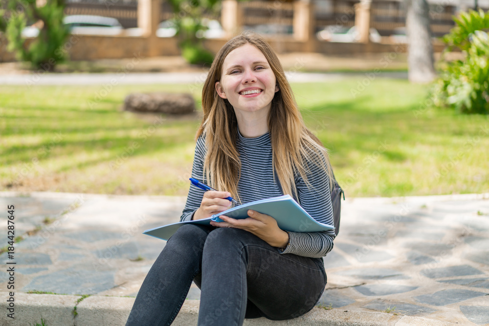Obraz premium Young blonde woman at outdoors holding a notebook
