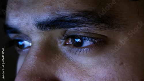 Foto close up detail of focused male eyes staring at computer monitor screen with blu
