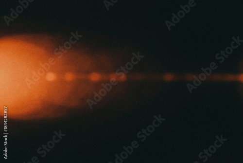Orange colored lens flare effect on black background