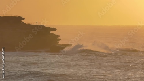 Ocean waves crashing into cliffs in golden early morning light