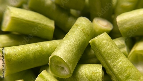 Fresh organic green beans and peas are sliced and chopped on a wooden table with raw onion and cucumber for a healthy vegetarian salad ingredient