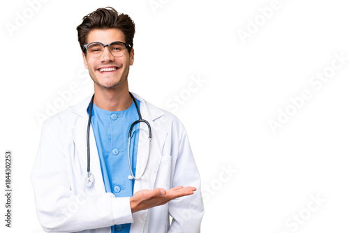 Young doctor man over isolated background presenting an idea while looking smiling towards