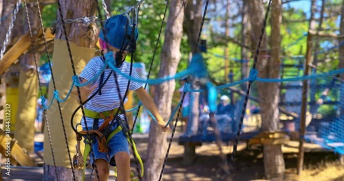 Child Navigating Rope Course in Adventure Park with Safety Gear