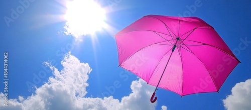 Wallpaper Mural Bright pink umbrella open against a vibrant blue sky with shining sun and white clouds, symbolizing sun protection and summer. Torontodigital.ca