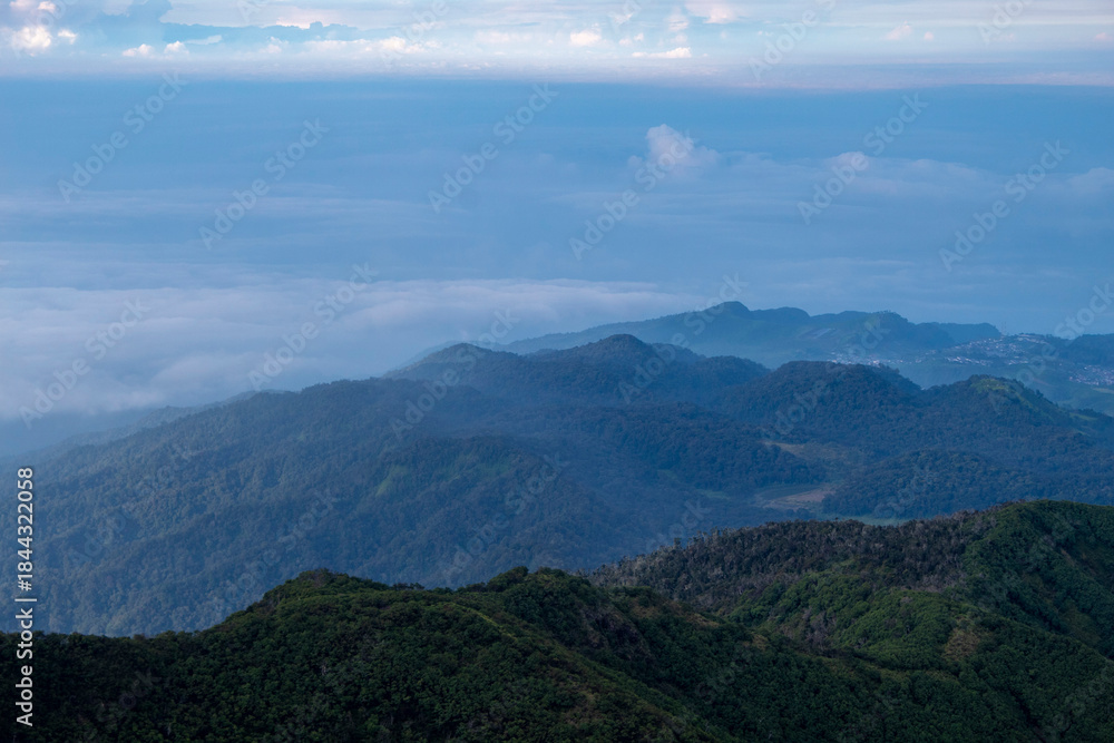 Obraz premium A breathtaking panoramic view of a lush green mountain range stretching into the misty horizon