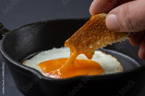 Canvas-taulu Toast dipping into runny egg yolk
