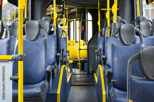Interior of an articulated bus, showing the modular seat layout, safety handrails, and the low-floor design for accessibility.