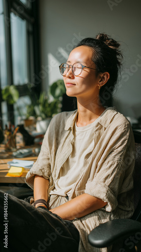 Nonbinary Southeast Asian office worker taking a peaceful mindfulness break during a busy day. Calm, inclusive, modern work-life balance moment. Person with eyes closed, peaceful expression, workplace