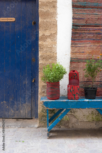 Rue d'Essaouira, porte bleue en bois, banc et plantes, tapis, Maroc
