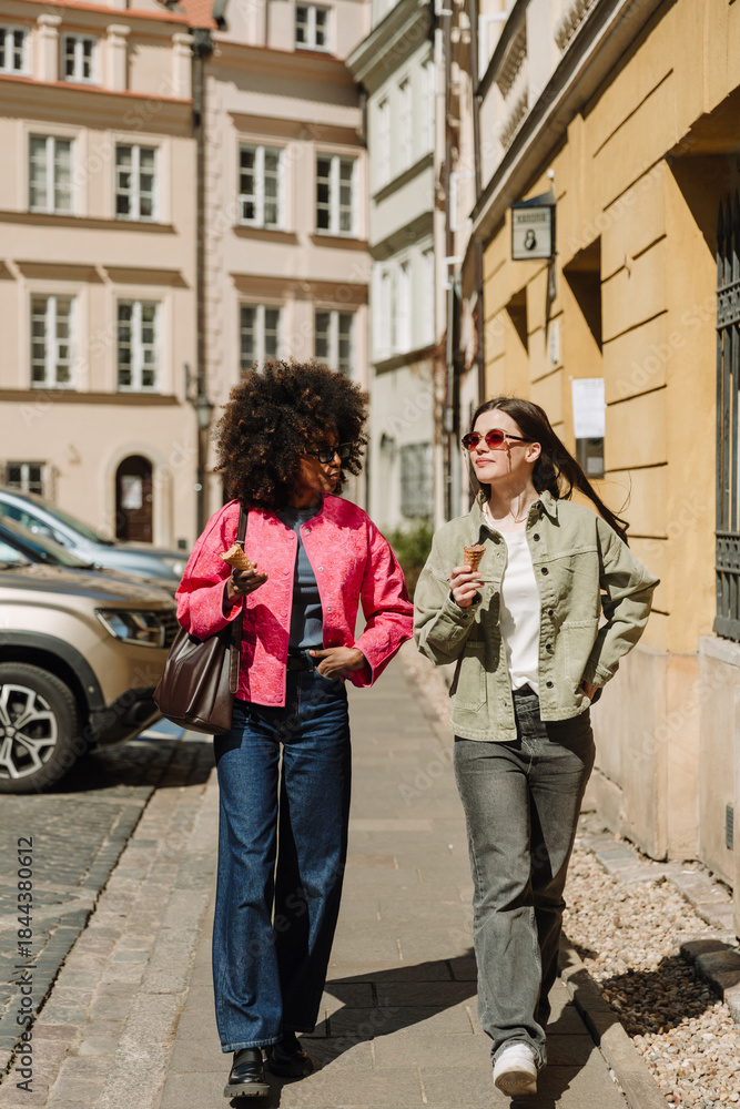Fototapeta premium A woman is talking to a female friend who is walking next to her while they are holding ice cream