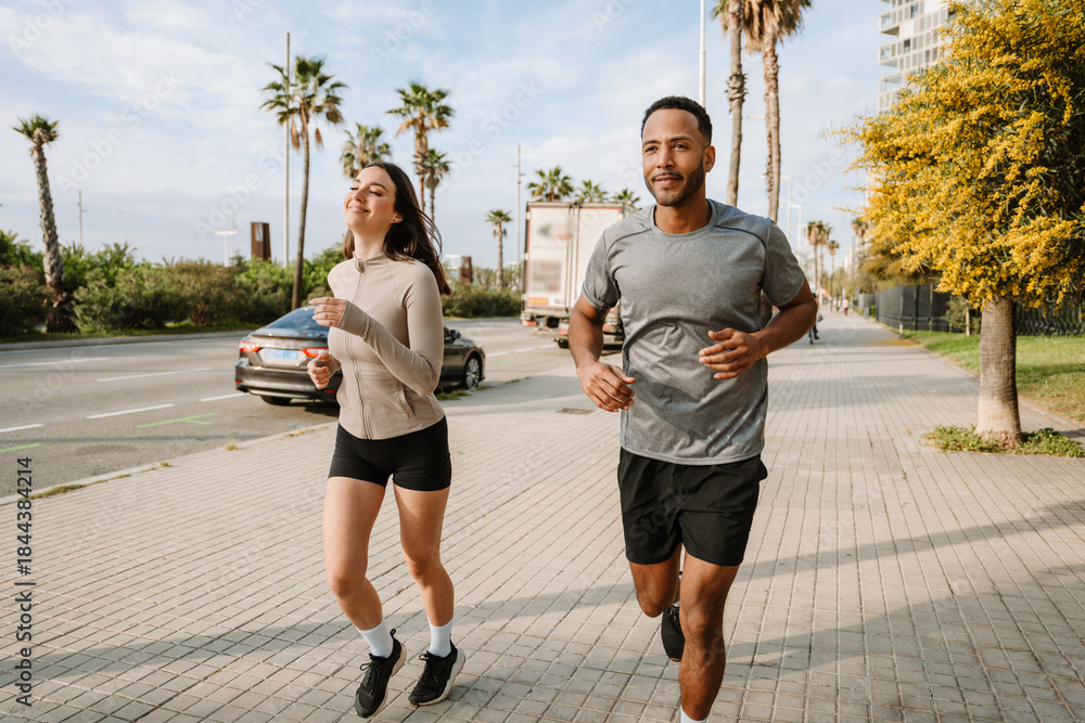 Obraz premium Female athlete smiling and running with male athlete