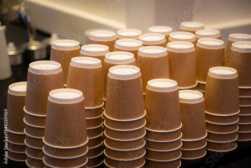 Brown paper coffee cups neatly arranged and stacked on a counter, ready for use in a cafe or event, emphasizing catering, organization, and sustainability