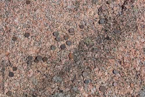 Close-up of Aljava Ukukivi (Offering stone of Uku) boulder with offering coins left on rock in sunny summer weather, Muhu, Estonia.