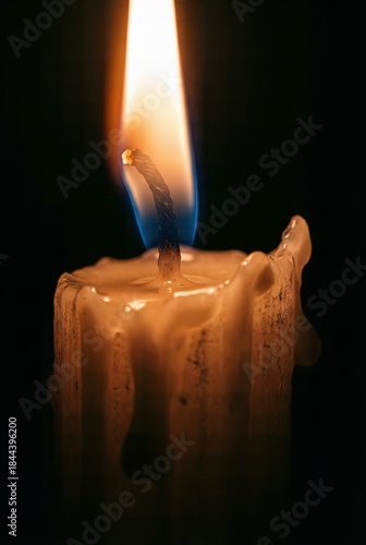 Single burning candle flame close-up in the dark vertical wallpaper.