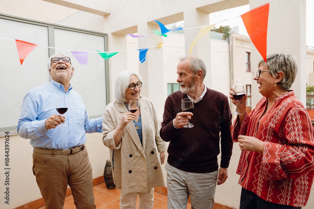Obraz premium Group of four friends standing and laughing while holding glasses