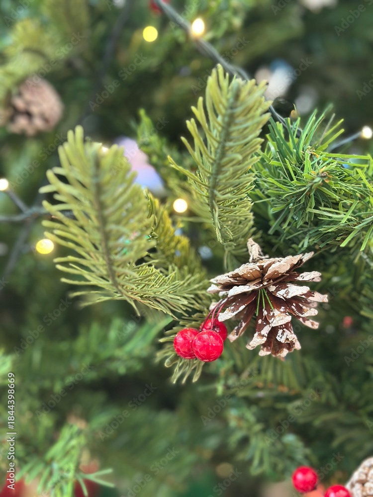 Fototapeta premium Season's greetings scene. Top view of Christmas decorations, balls, rustic star, holly berries, frosty spruce branches, confetti on green backdrop, perfect for messages or promo. text space concept