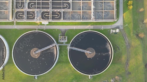 Aerial view of water treatment facility showcasing circular tanks and machinery. Sewerage system surrounded by greenery. Modern industrial plant of big city. Ecology friendly factory