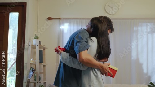 Love young couple shares happy romantic embrace at home, exchanging valentine gifts, showing deep affection for special day lovers celebration, creating heartwarming connection.