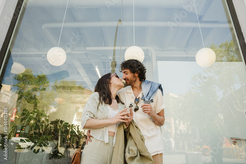 Fotografie A man hugs a woman who is holding a phone while they stand and are about to kiss