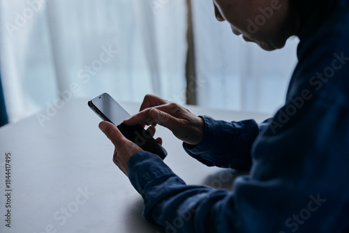 部屋でスマホを操作するシニア女性