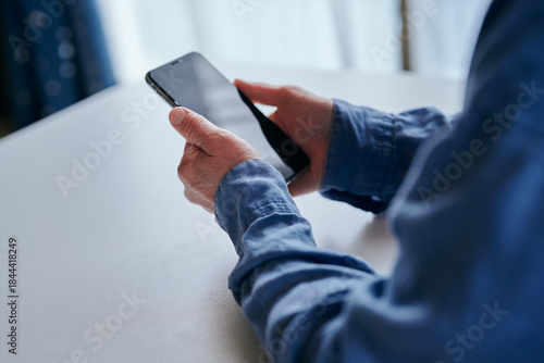 部屋でスマホを操作するシニア女性