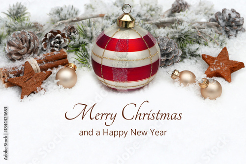 Christmas card: Christmas greetings against a winter backdrop with Christmas decorations, baubles, and fir branches in the snow. Merry Christmas and a Happy New Year.