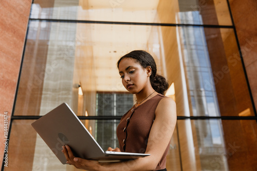 Foto A female worker is typing on a laptop she is looking at and holding
