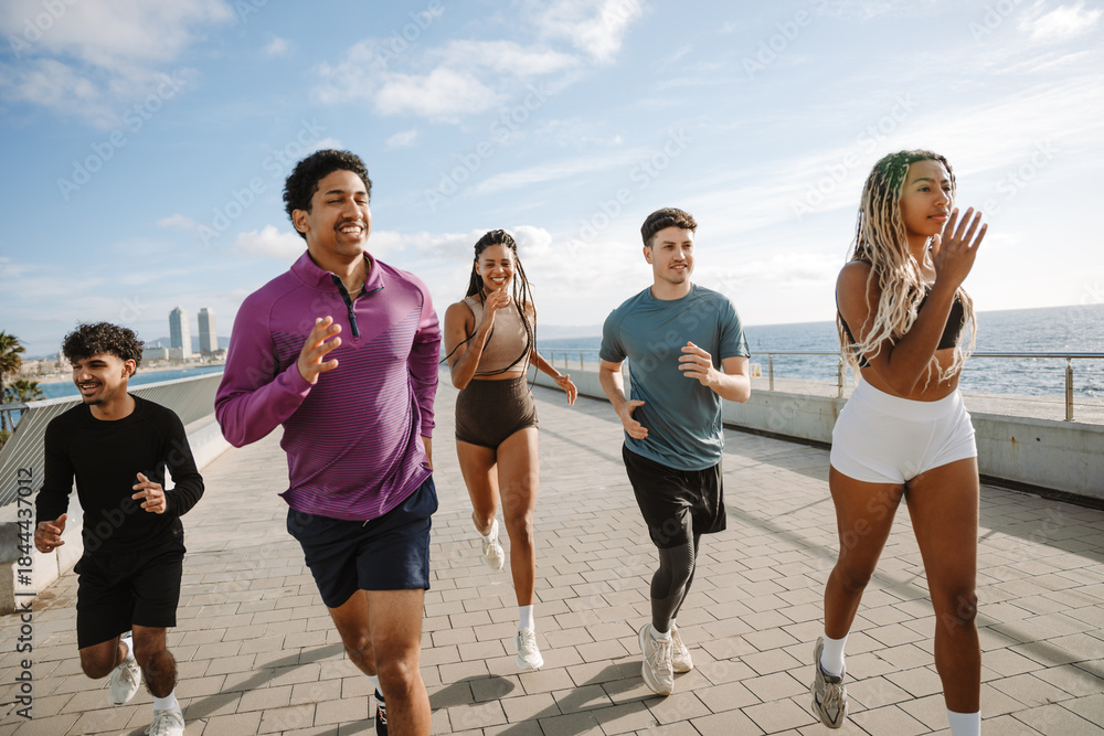 Obraz premium Group of four athletes laughing while running next to female athlete