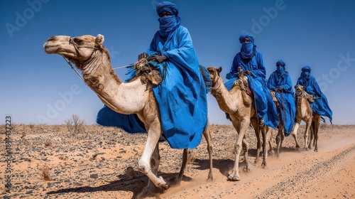Caravan of the Desert: A caravan of traditionally attired travelers traverse the sandy expanse, atop majestic camels against the azure sky, evoking the timeless allure of the Sahara desert.