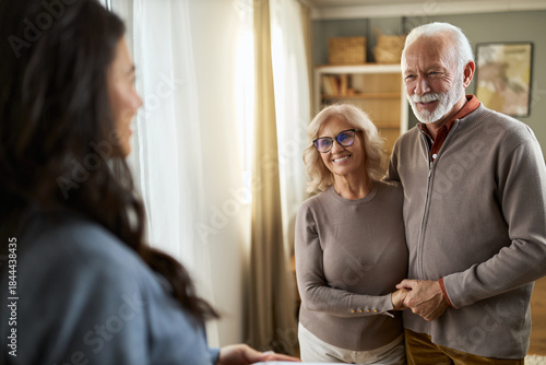 Happy senior couple talking to their female advisor at home