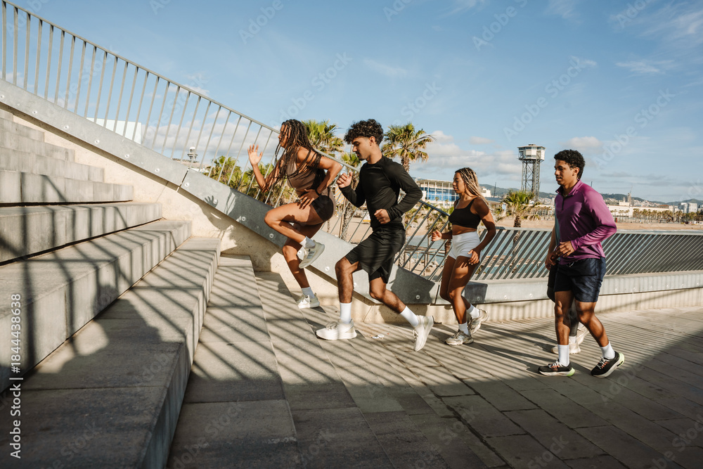 Fototapeta premium A female and male athlete run up the stairs while other male and female athletes are behind them