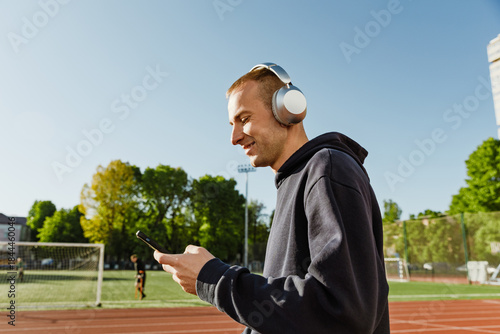 Man looking at phone and smiling while listening to headphones