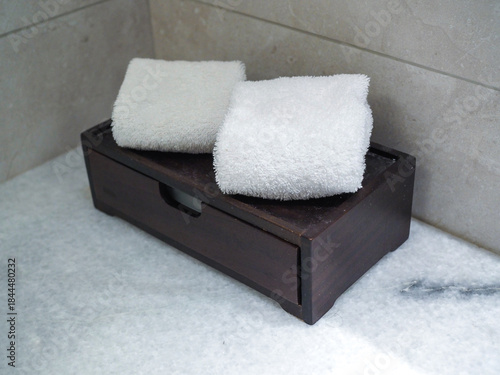 A wooden soap and toothbrush holder sits on a clean white towel in a spa-like bathroom setting.