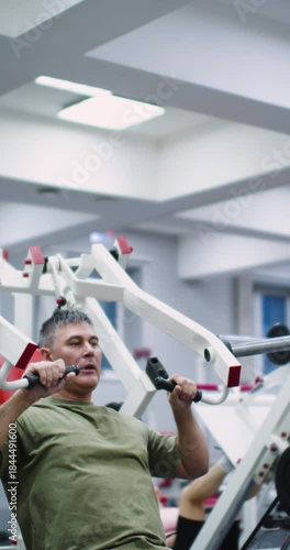 4K slow-motion video of a Caucasian man performing bench presses on a hammer machine for chest muscle activation. Gym workout. Bench press for deltoids in hammer machine.