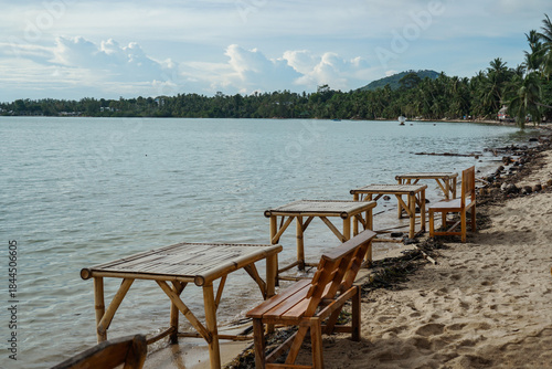 Tropical beach scene with beach loungers and palm trees. Beach with sun loungers casting long shadows on sand. Sun loungers and clear blue sky, perfect for relaxation.