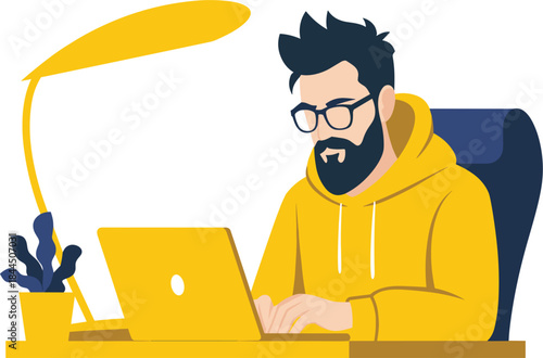 Bearded man in yellow hoodie working on laptop under desk lamp light.