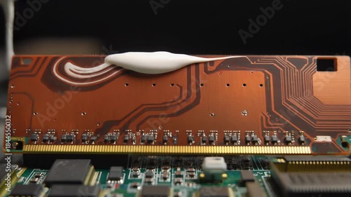 Applying thermal paste to a computer RAM module for improved heat dissipation and performance.