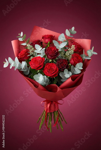 Bouquet of flowers with a floral design red rose and soft eucalyptus branches , wrapped in crisp red  paper with ribbon. Dark red background. Romantic, love, Valentine's day, wedding, holidays