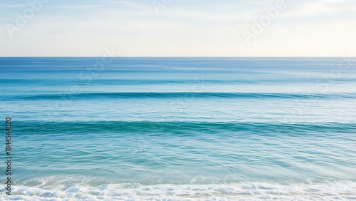 Fototapeta Naklejka Na Ścianę i Meble -  A tranquil seascape captures the movement of multiple turquoise and blue waves rolling gently towards the coastline