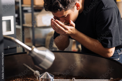 Fotografie Barista holding in his hands fresh roasted coffee beans and smelling them to che