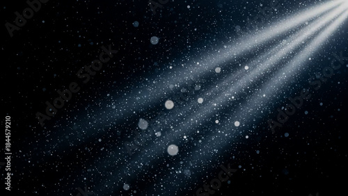 A closeup shot captures a beam of light illuminating floating dust particles against a dark background. The bokeh effect adds a magical, dreamy quality, suitable for various design projects.