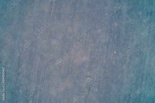Minimalist texture of dry, dusty soil surface with subtle granular details showing abstract background and geological layers aerial view