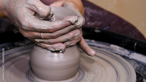 Man makes a clay pot or vase on a potter's wheel
