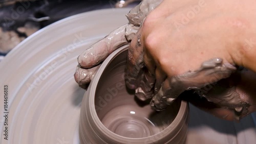 Man makes a clay pot or vase on a potter's wheel